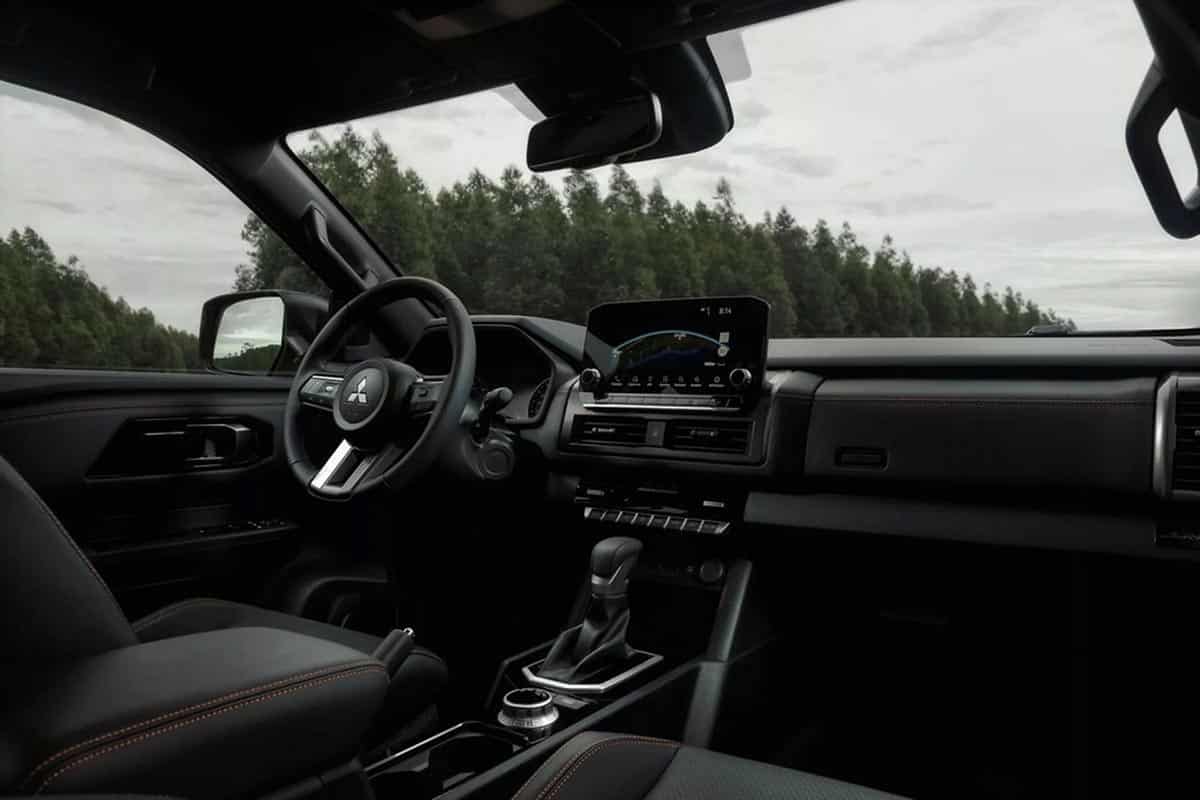Interior of a Mitsubishi L200 Savana featuring a utilitarian dashboard and central display screen